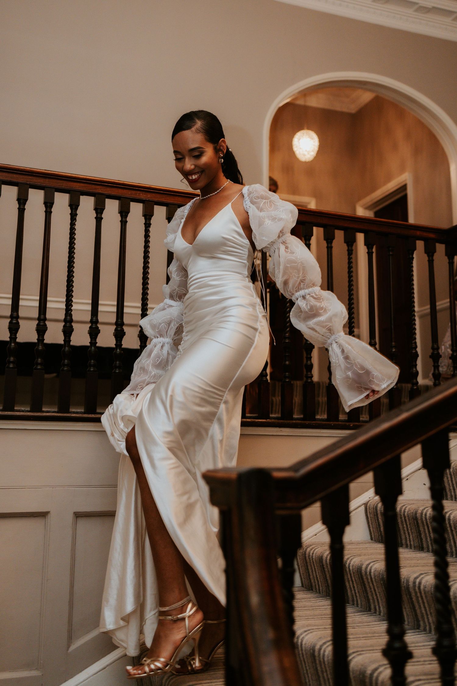 Elegant wedding dress with dramatic puff sleeves showcased on grand staircase.