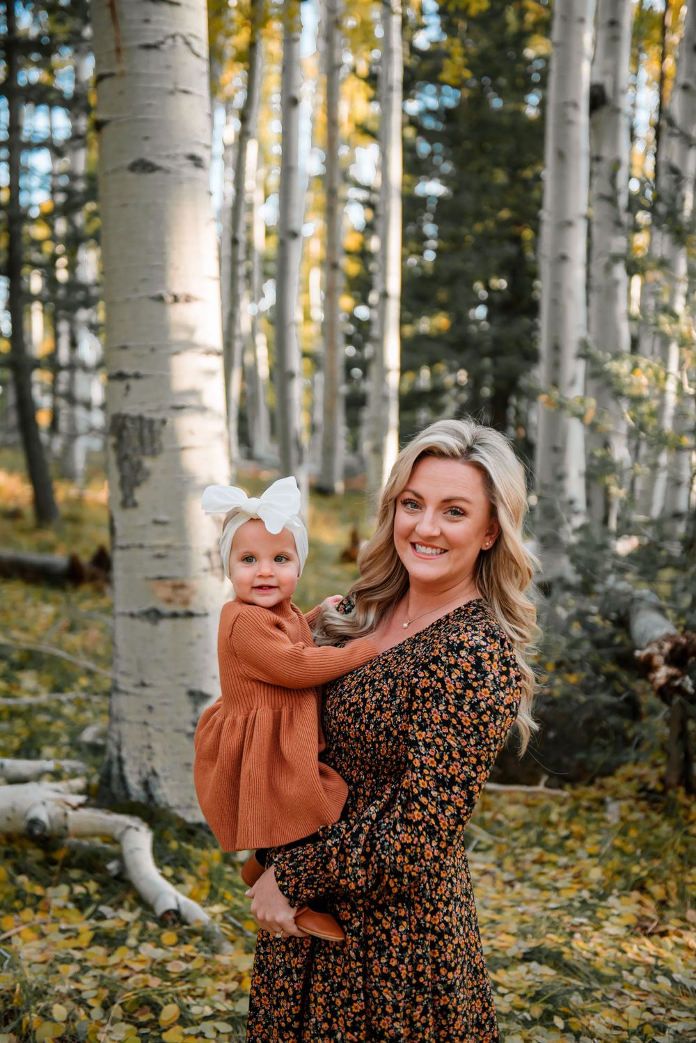 Mother and child sharing a joyful moment in a golden aspen forest during fall.