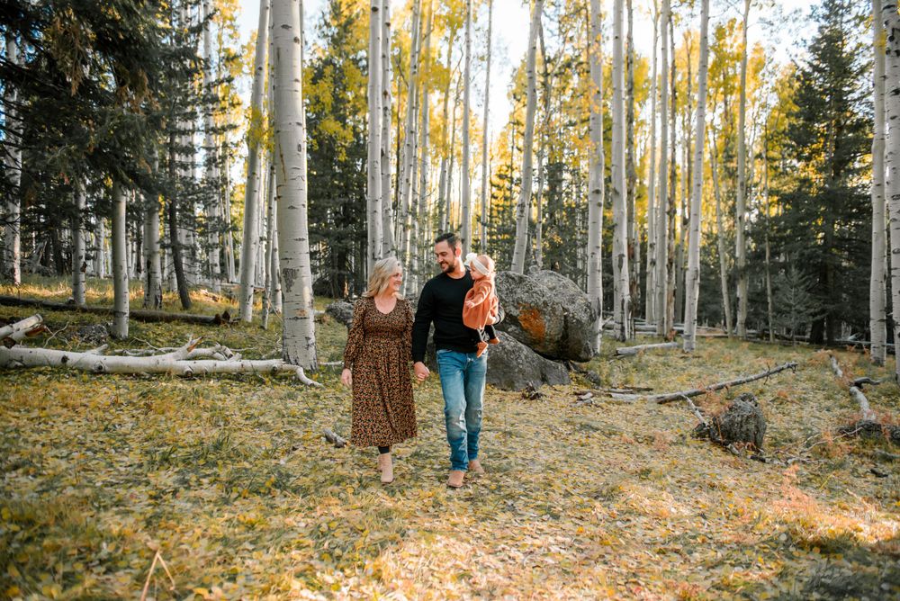 A couple walks hand in hand through a scenic aspen grove with golden fall foliage.
