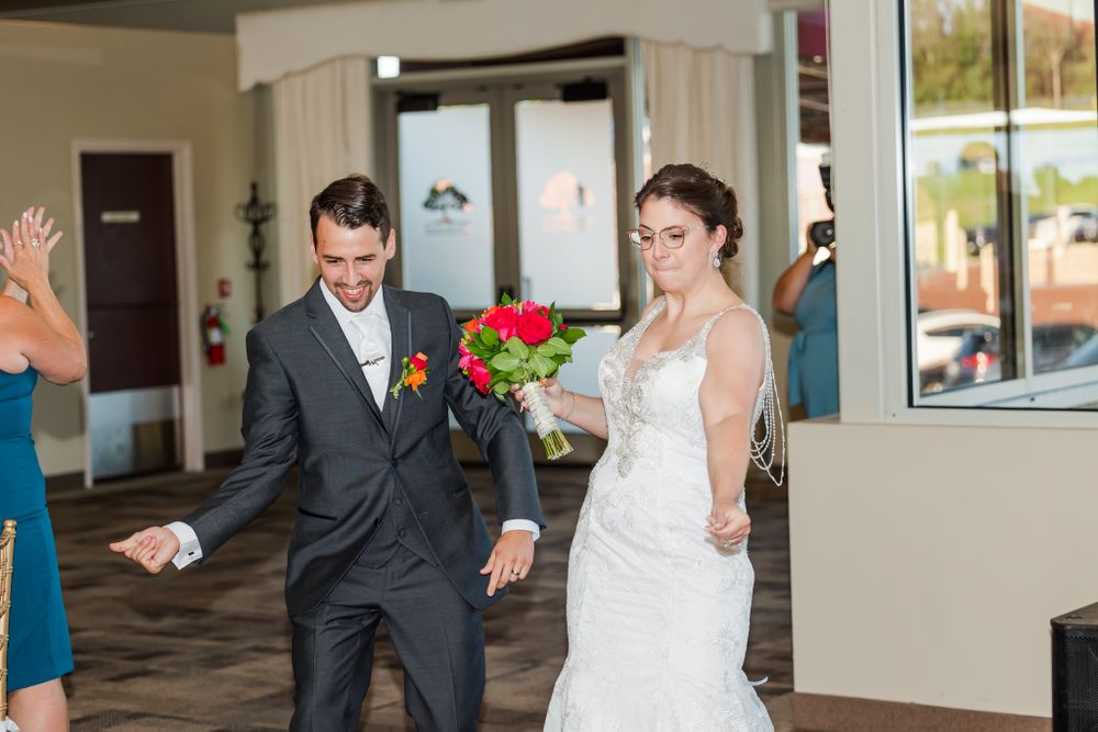 Couple celebrates with energetic poses during their wedding entrance.