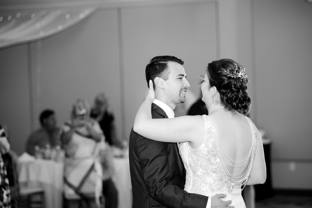 Dancing couple shares intimate moment during wedding reception in black and white.