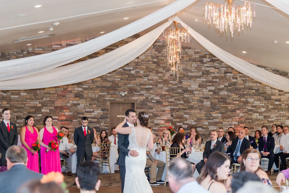 Wedding reception venue with stone walls, crystal chandeliers and white fabric draping overhead.