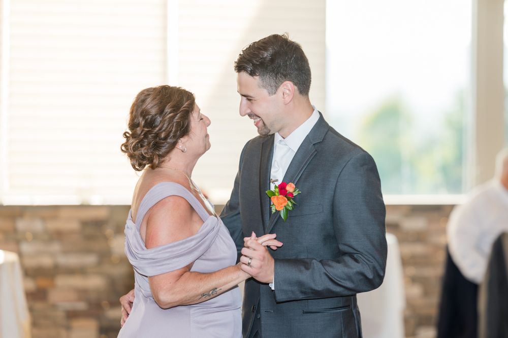 Wedding couple sharing an intimate dance moment in front of stone wall backdrop.