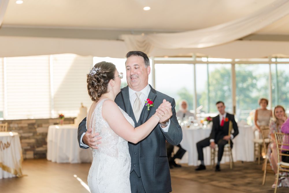 Bride and groom dancing together at wedding reception with natural window light.