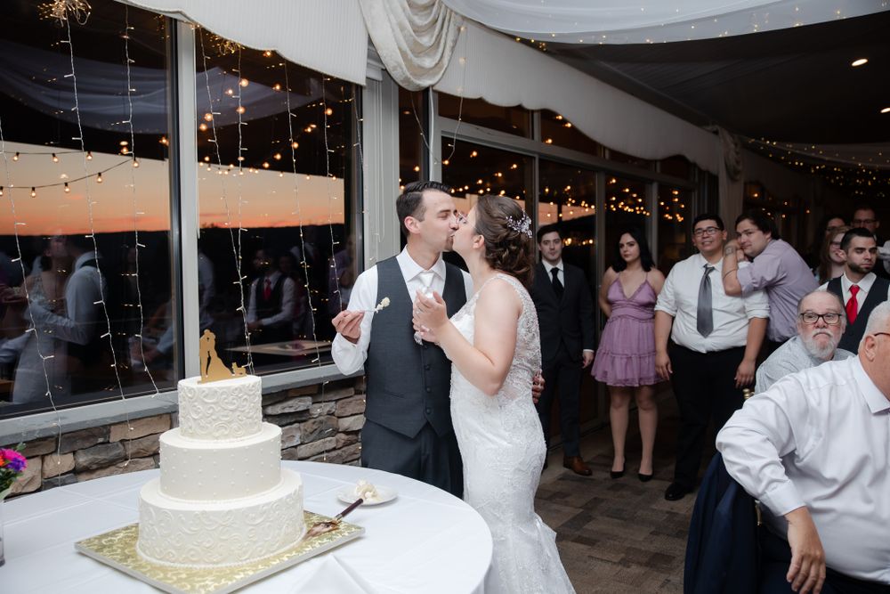 Wedding reception scene with white cake and string lights decorating indoor venue.