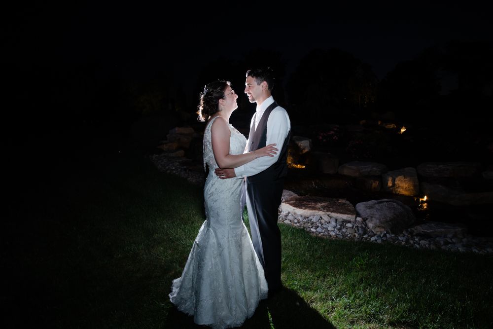 Romantic nighttime dance between couple on outdoor grass with lighting.