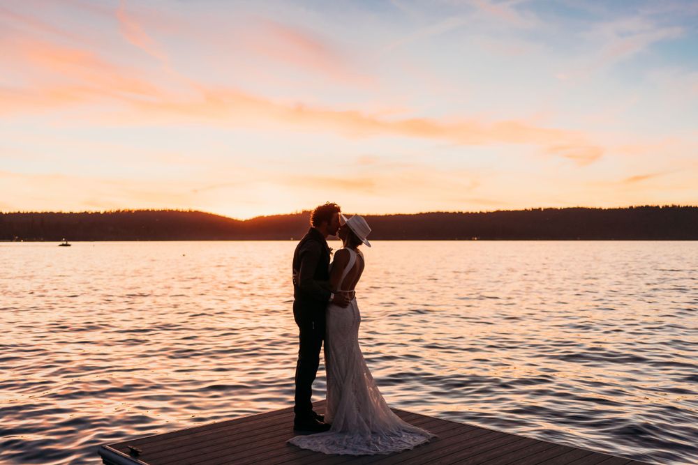 Romantic silhouette of a couple against sunset over a lake.