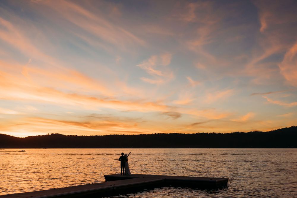 Silhouetted figures on a dock during golden hour sunset.