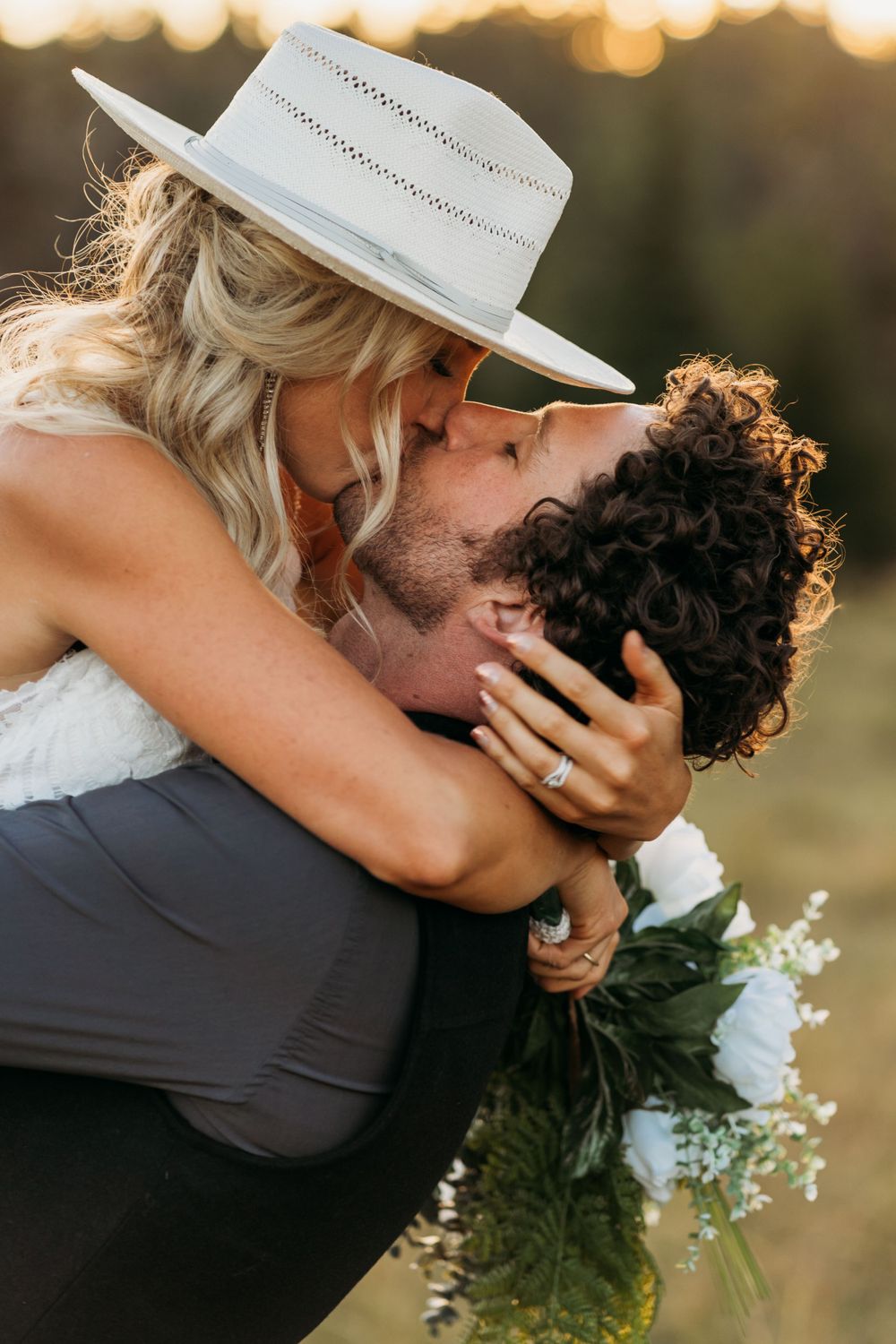 Intimate embrace with white hat against golden sunset background.