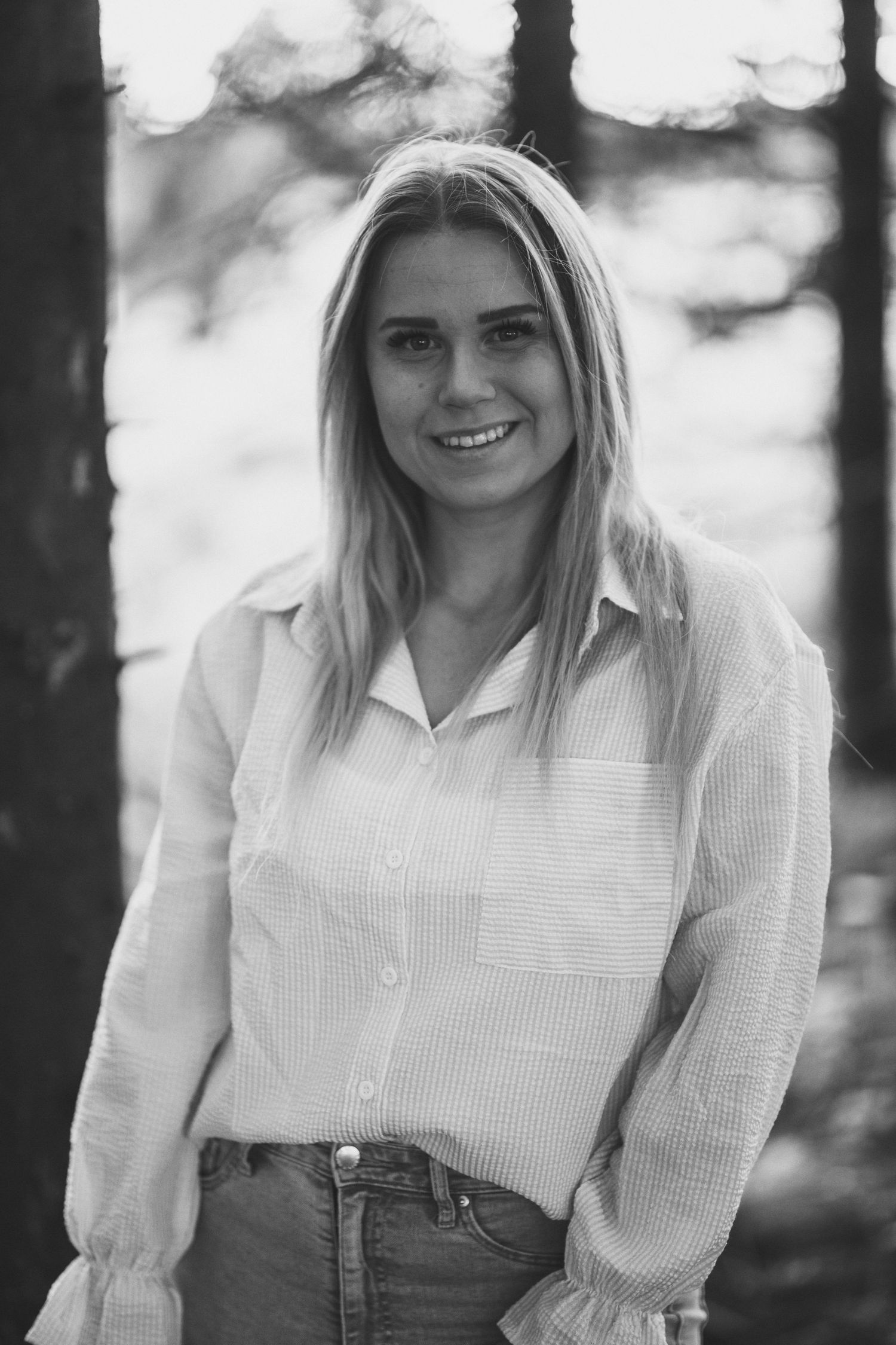 Classic black and white headshot of a woman smiling in a casual white shirt.