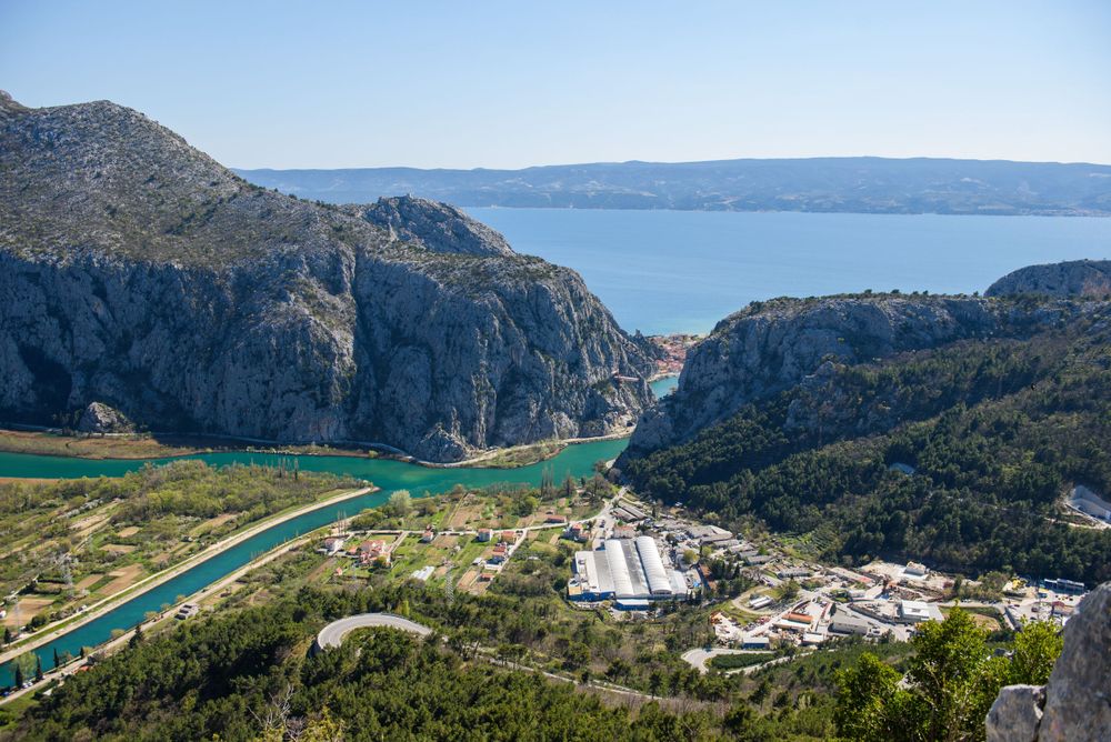 Dramatic canyon landscape with river and settlement nestled between mountains in Croatia.