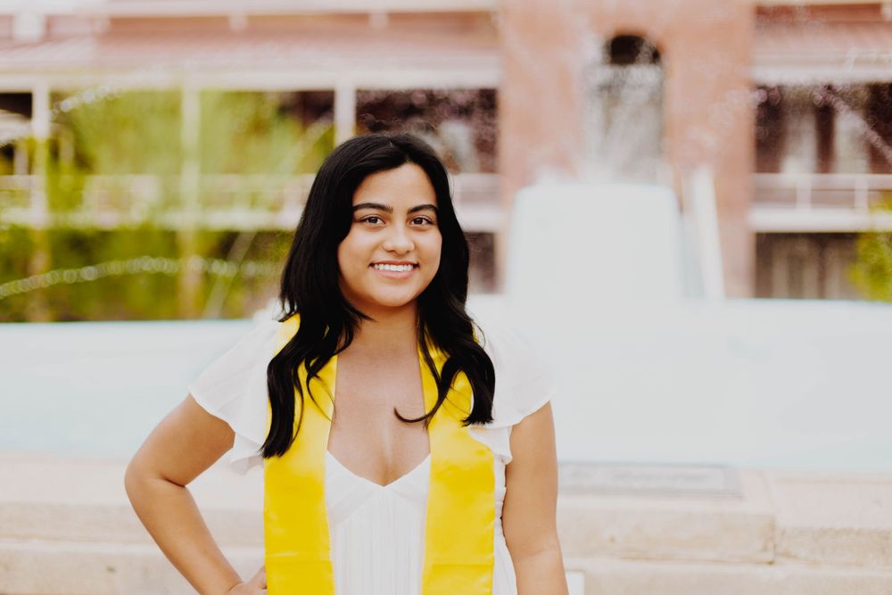 Graduation photos showcase white dress and yellow college stoles against brick building backdrop.