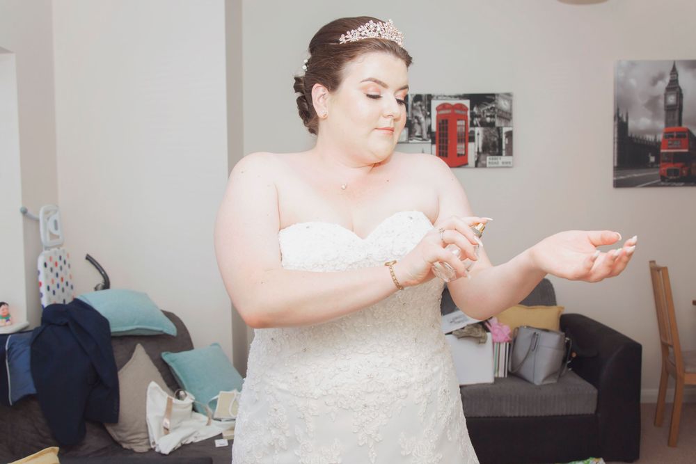 Bride putting on perfume for finishing touches