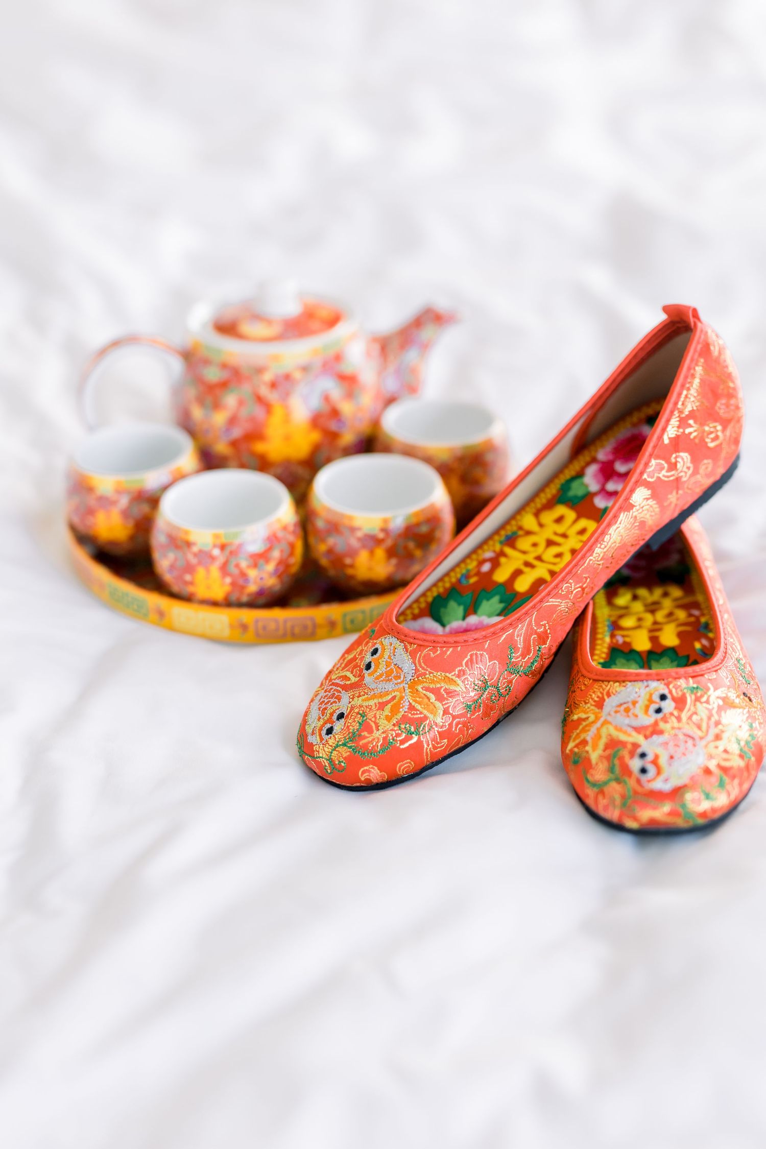 Oriental tea set and matching embroidered shoes in coral and gold patterns.
