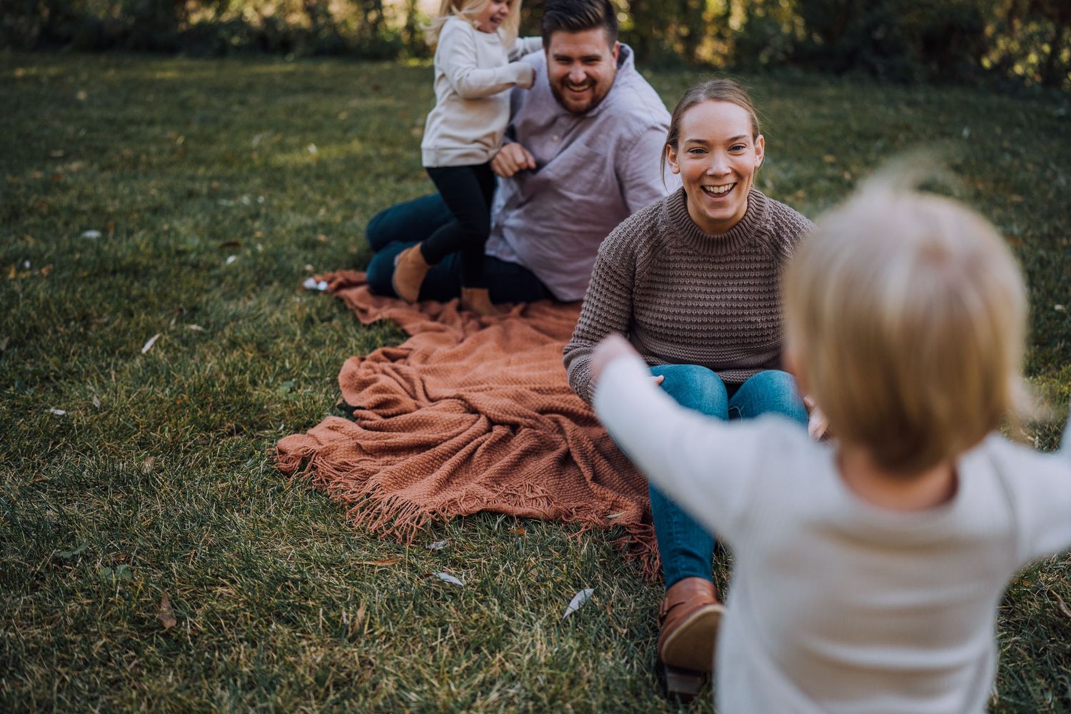 A candid family moment of joy and laughter during an outdoor autumn photoshoot.