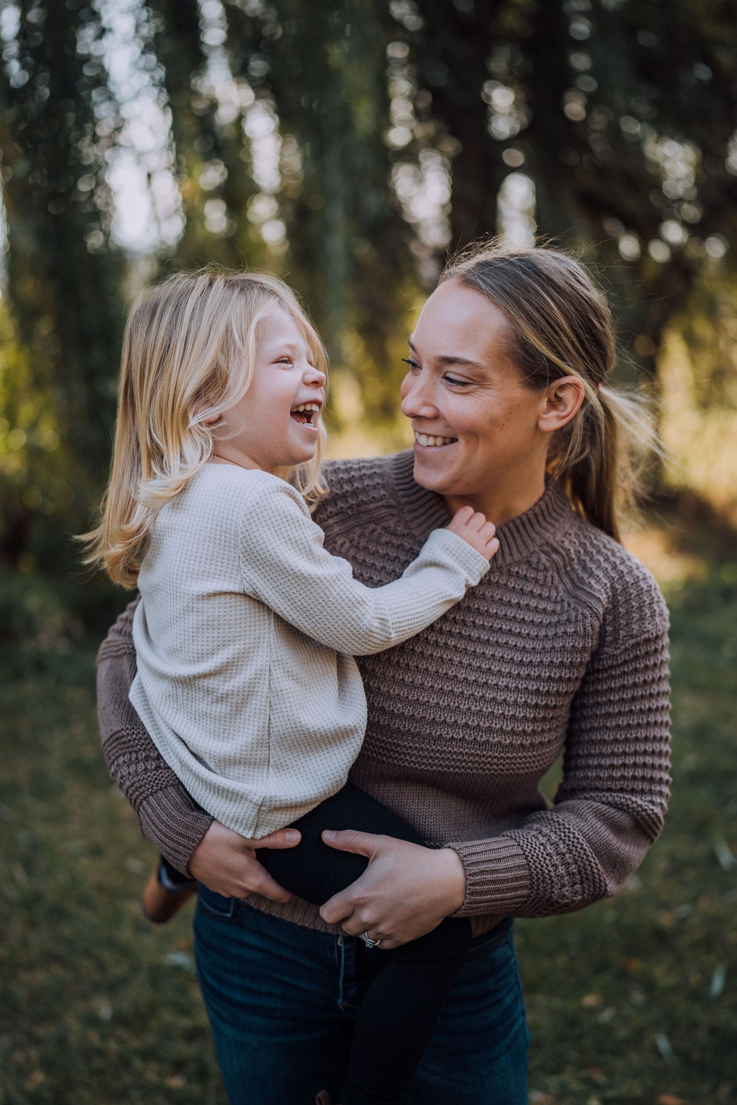 A heartwarming moment of laughter between parent and child in an autumn forest setting.
