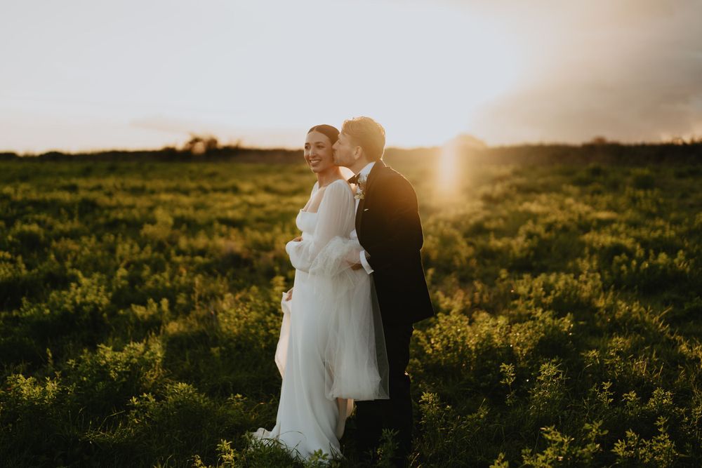 Couple embracing in a sunlit meadow during golden hour.