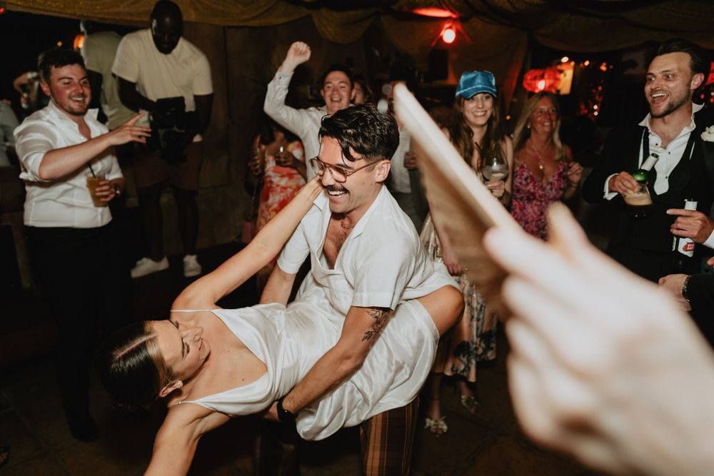 Wedding guests dance and celebrate on a lively dance floor at an evening reception.