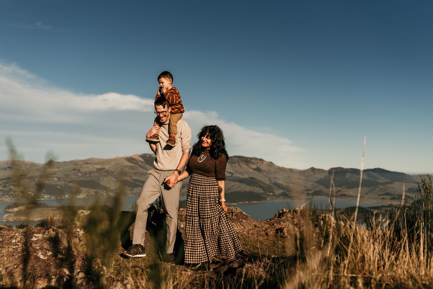 Family enjoying scenic mountain views together while standing on rocky overlook during sunset.