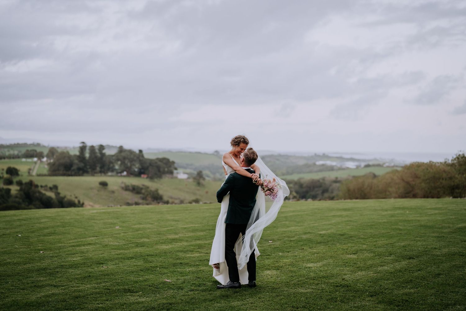 A romantic moment captured on a hilltop with sweeping views of the countryside.
