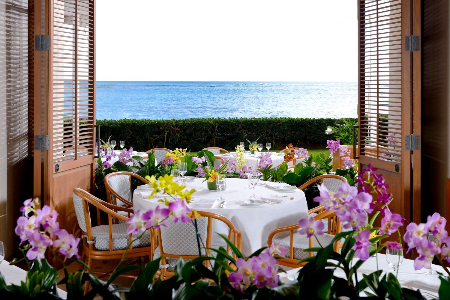 A romantic oceanview dining table adorned with colorful orchids framed by wooden shuttered doors.
オーキッズレストランでのパーティー