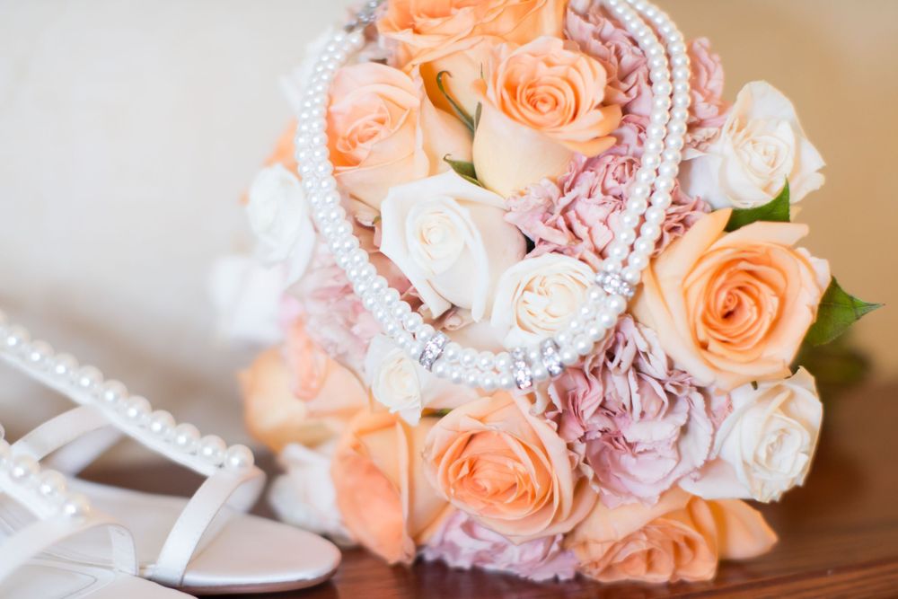 Wedding bouquet featuring peach roses with delicate pearl details.