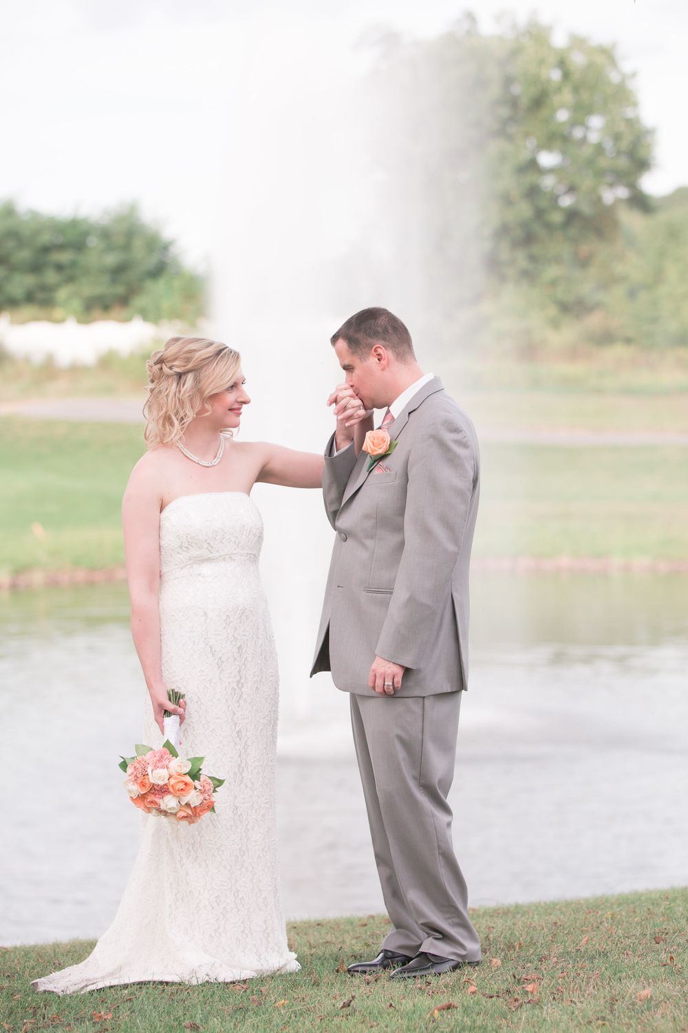 Sweet moment between couple by water fountain during outdoor wedding photoshoot.