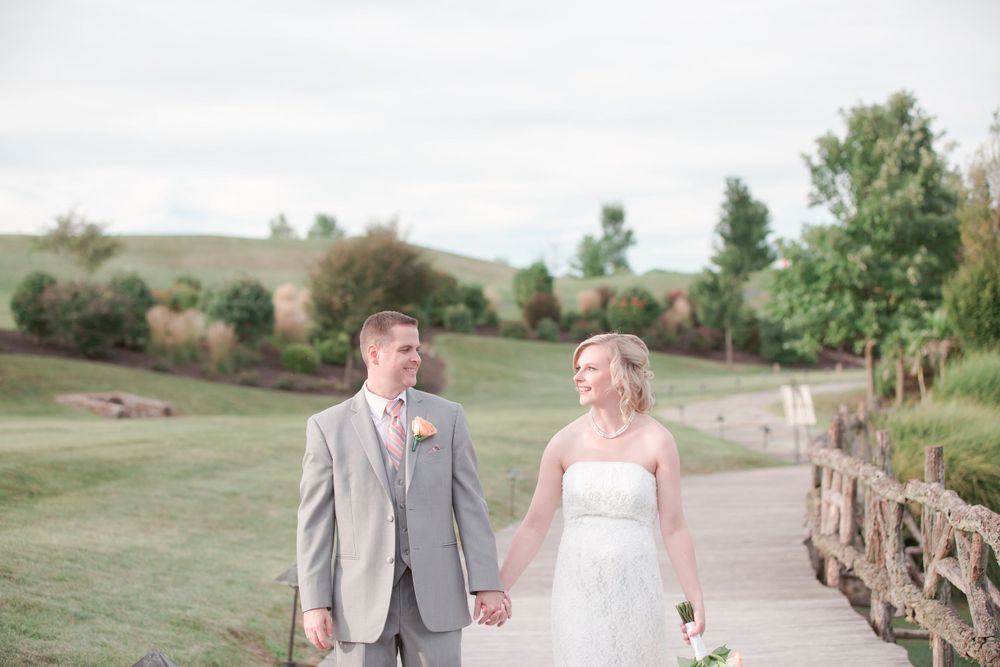 A couple walks hand in hand along a stone-lined pathway through a scenic landscape.
