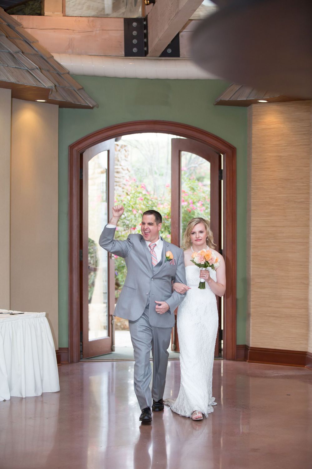 A couple makes their grand entrance through an arched doorway at their wedding venue.