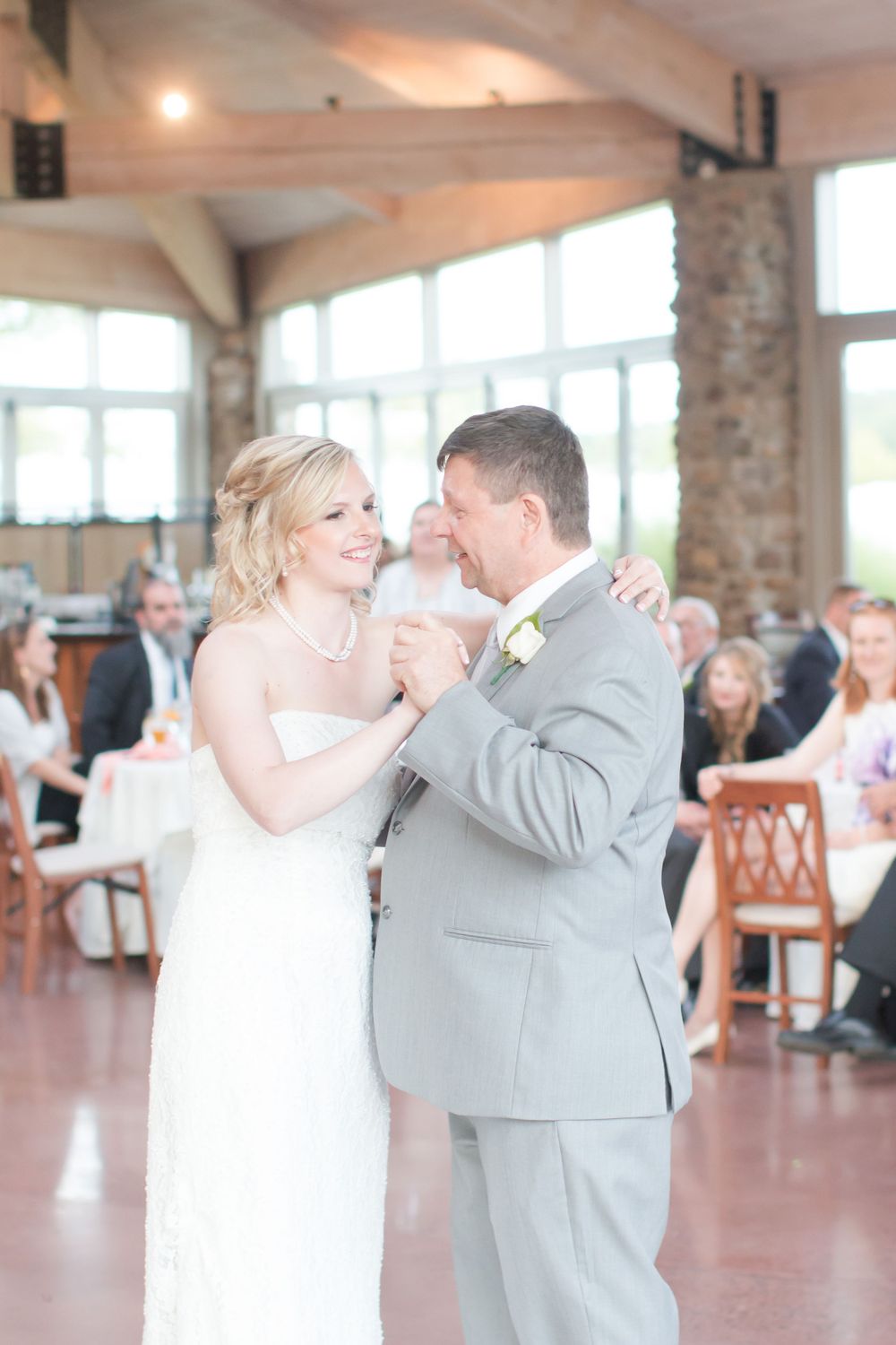 A couple shares their first dance in an elegant venue with stone pillars and natural lighting.