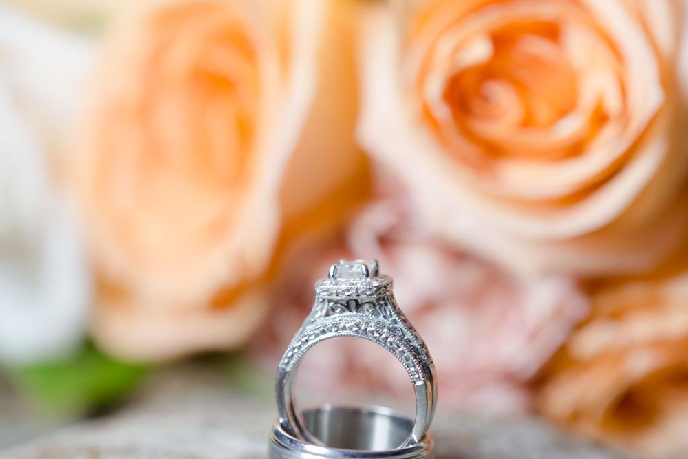 Diamond engagement ring and wedding band photographed with peach roses in the background.