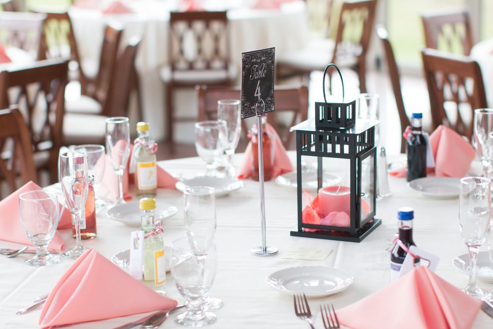 Elegant wedding reception table setting with pink napkins and black lantern centerpieces.