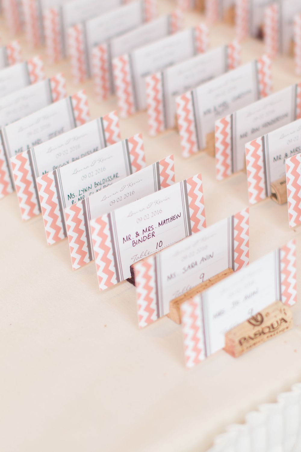 Coral and white patterned place cards arranged in neat rows for wedding reception seating.
