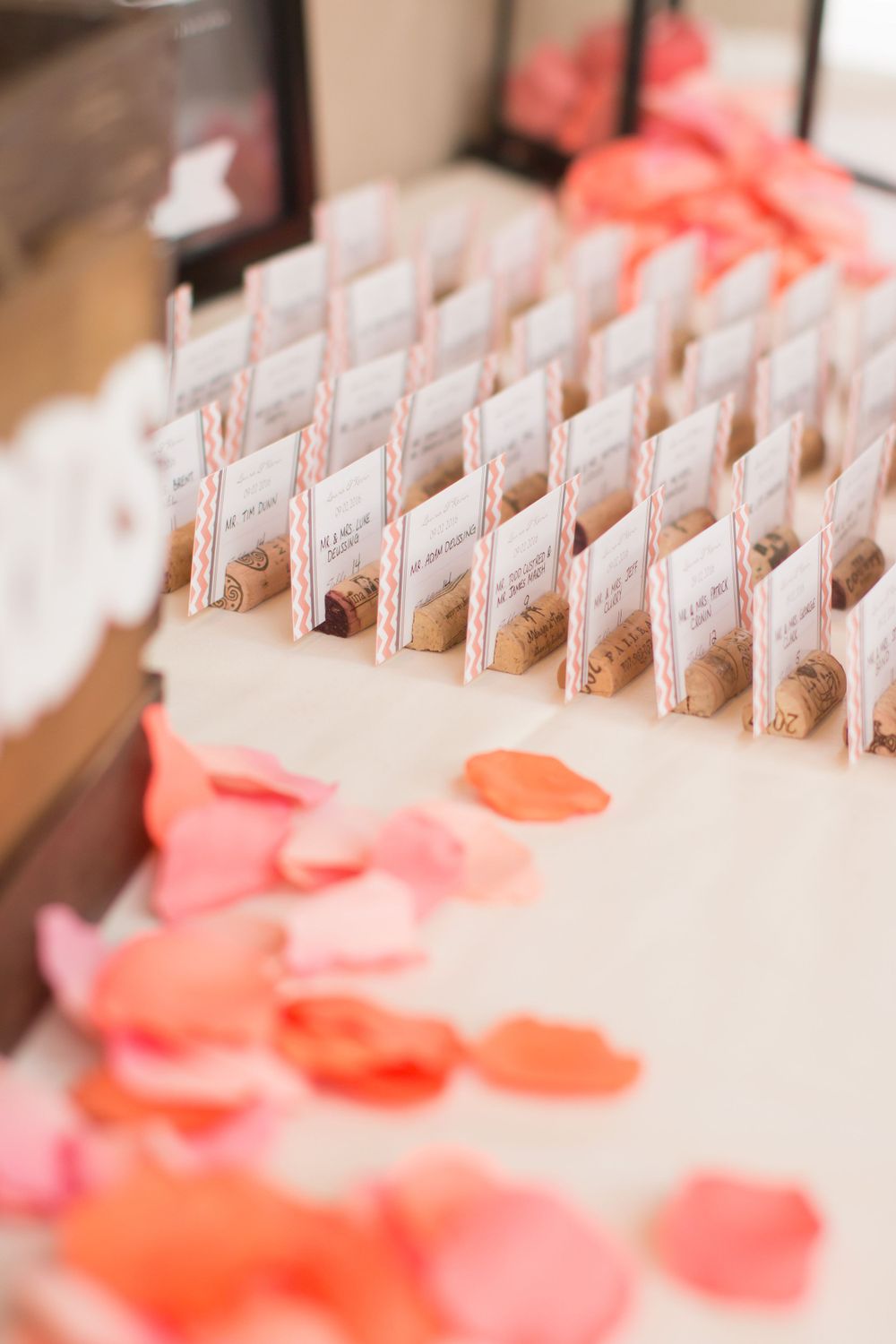 Wedding place cards displayed with coral flower petals scattered around.