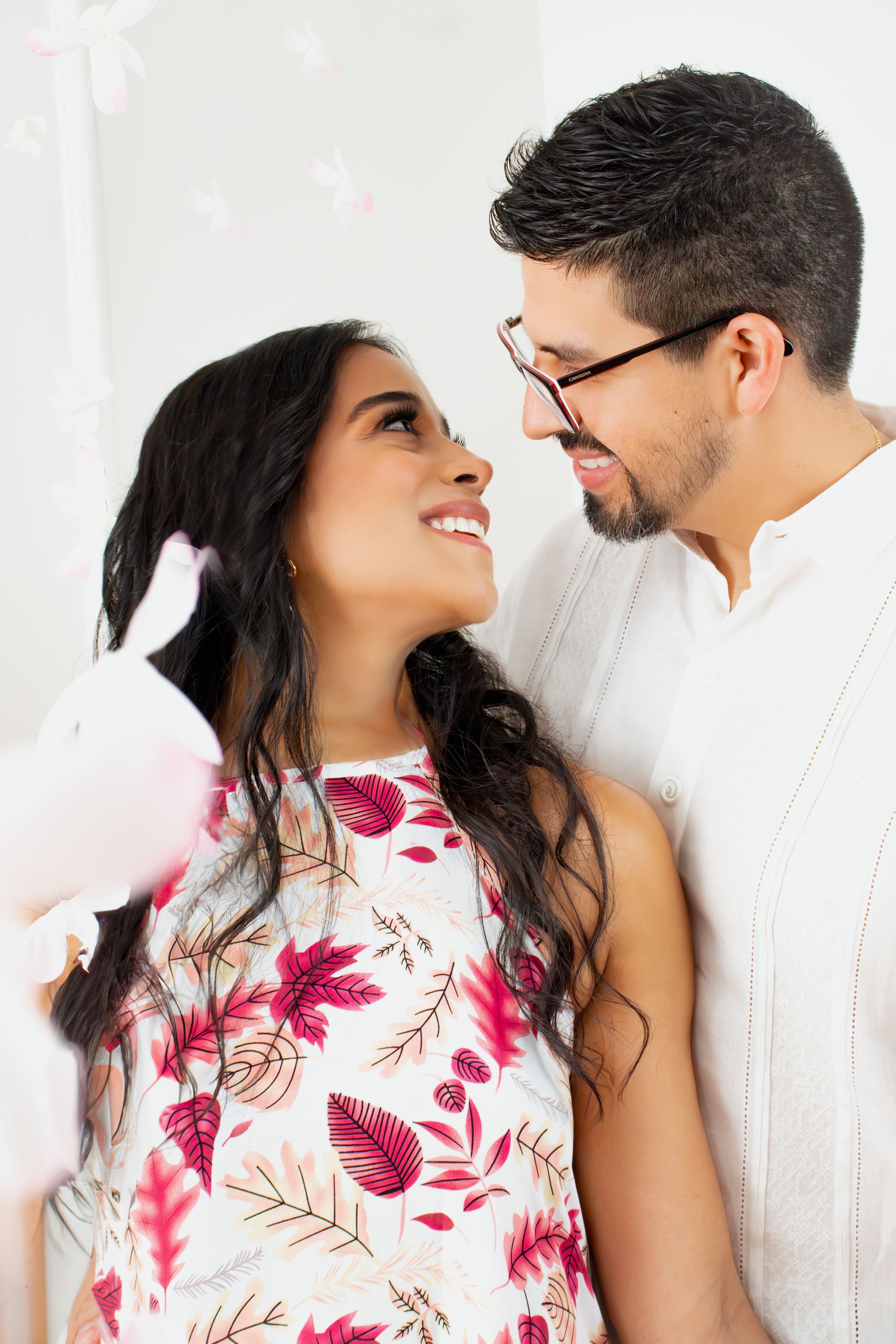 Couple shares an intimate moment wearing coordinated white and floral outfits against a white background.