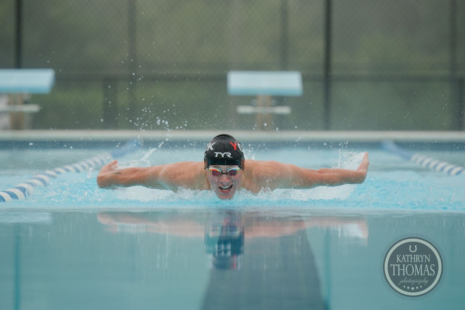 A swimmer performs the butterfly stroke in a competition pool with perfect form.