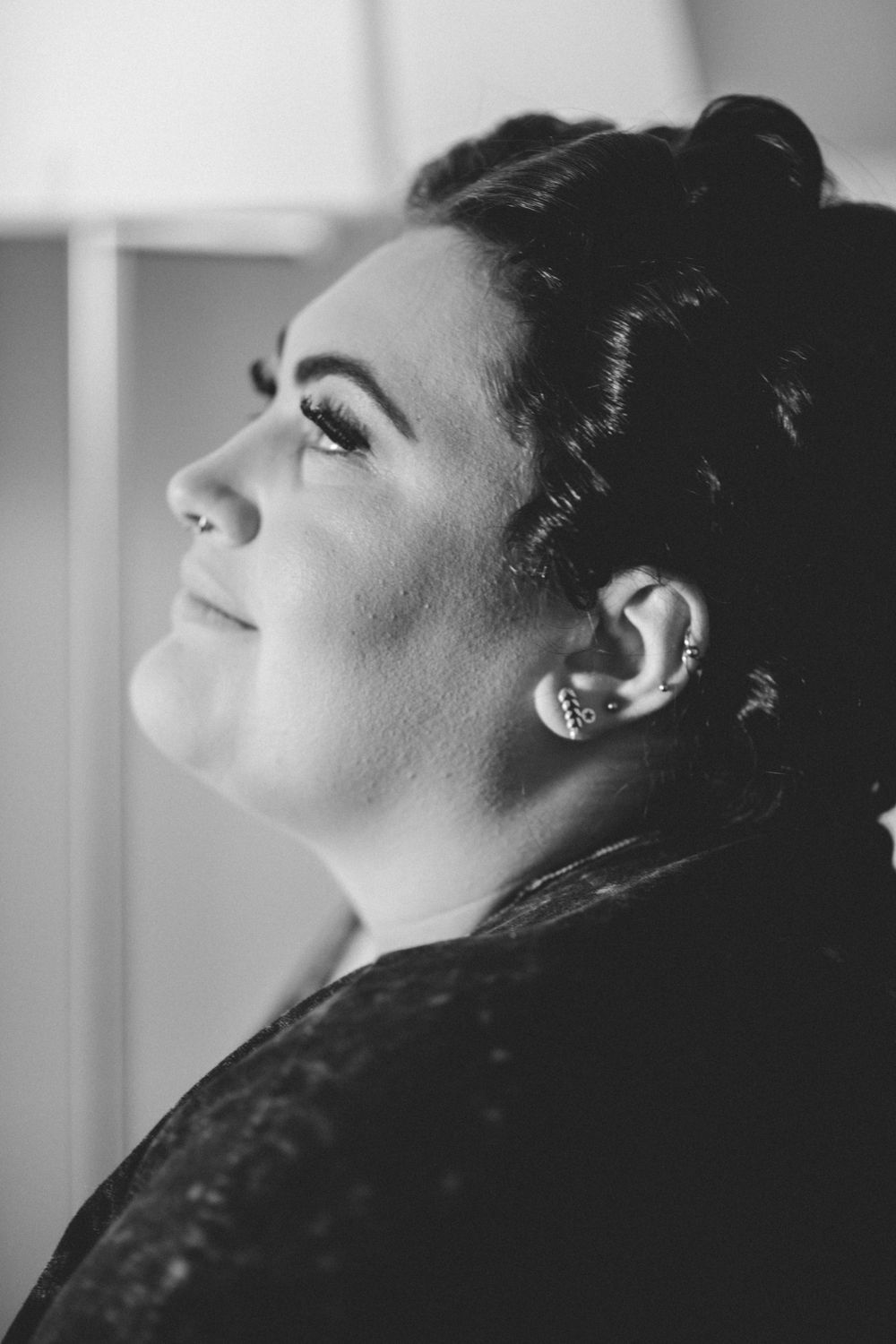 A dramatic black and white profile portrait showcasing elegant hair styling and jewelry.