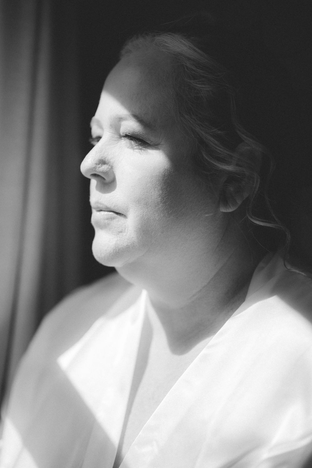 Artistic black and white profile portrait in soft window light.