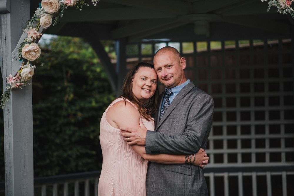A romantic moment captured under a floral-decorated gazebo during a wedding celebration.