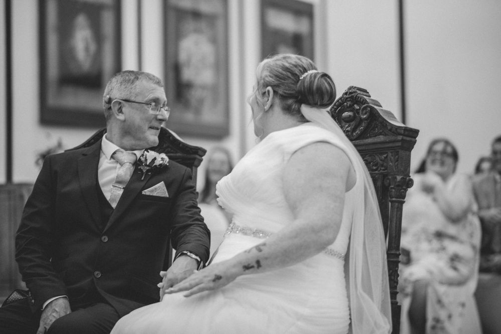 An intimate black and white wedding moment captured during the ceremony with classic formal attire.