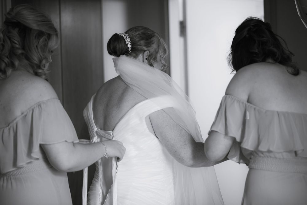 Bridesmaids in light-colored dresses help with final wedding preparations.