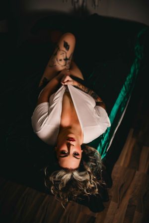 Overhead boudoir portrait in white shirt on wooden floor.