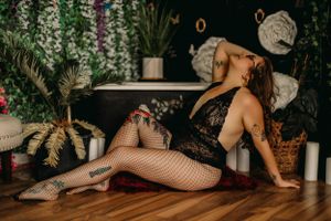Boudoir scene with fishnets among tropical plants and candles with boho decor.