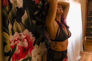 Silhouetted figure against floral wallpaper in moody lighting.