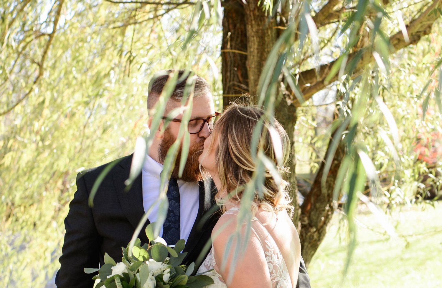 Romantic wedding portraits captured beneath swaying willow branches.