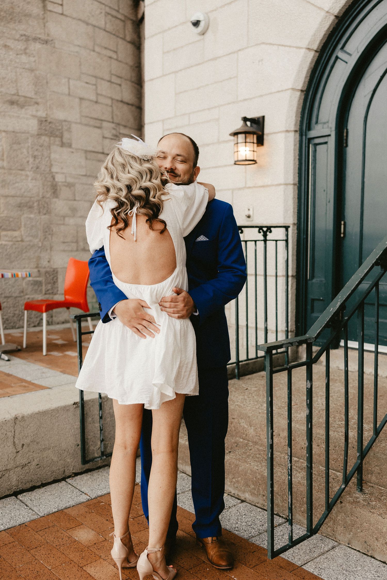 A sweet embrace between newlyweds on steps near an arched doorway.
