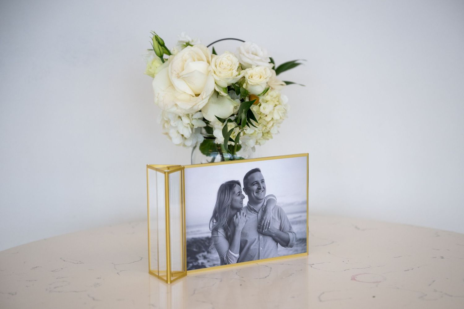 Wedding detail shot featuring white floral arrangements and framed photos on display.