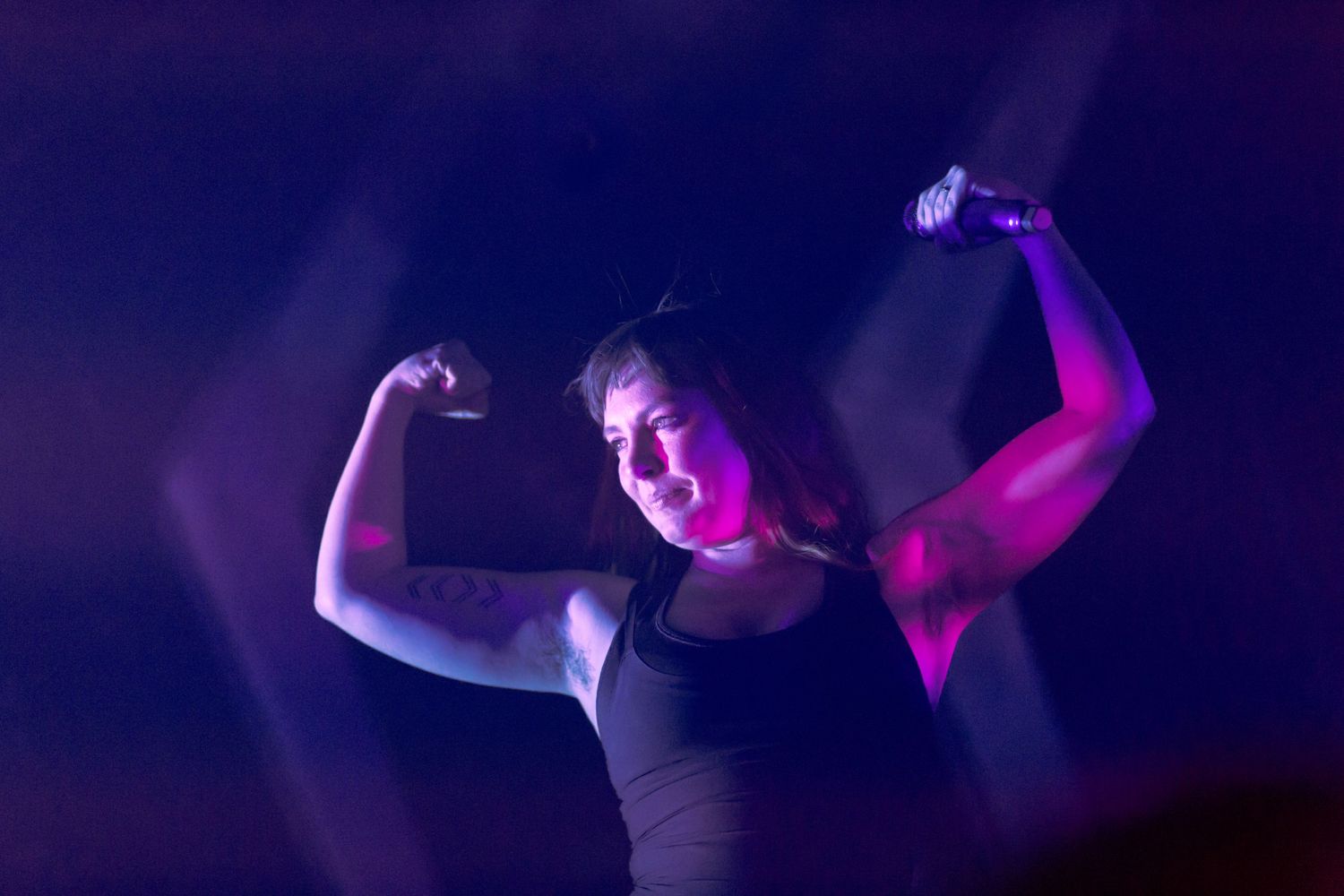 Silhouettes dance under purple stage lighting at a performance.