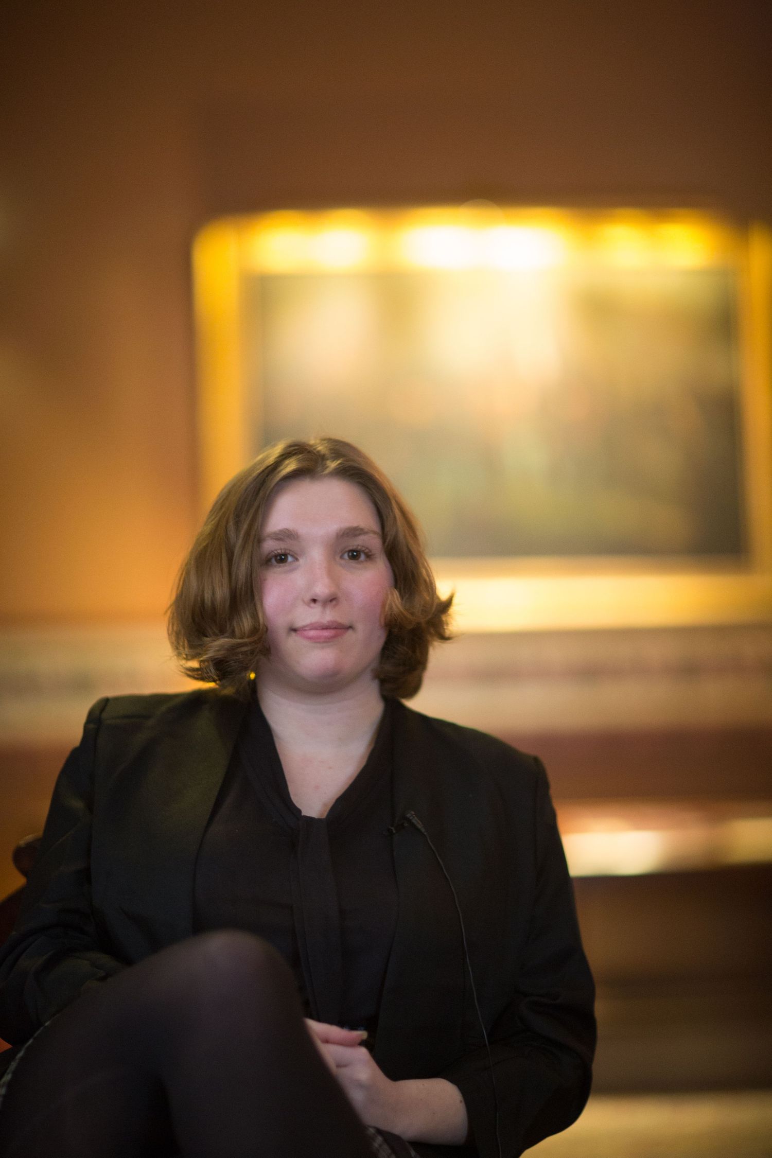 A figure in black attire appears in a series of atmospheric golden-lit portraits.
