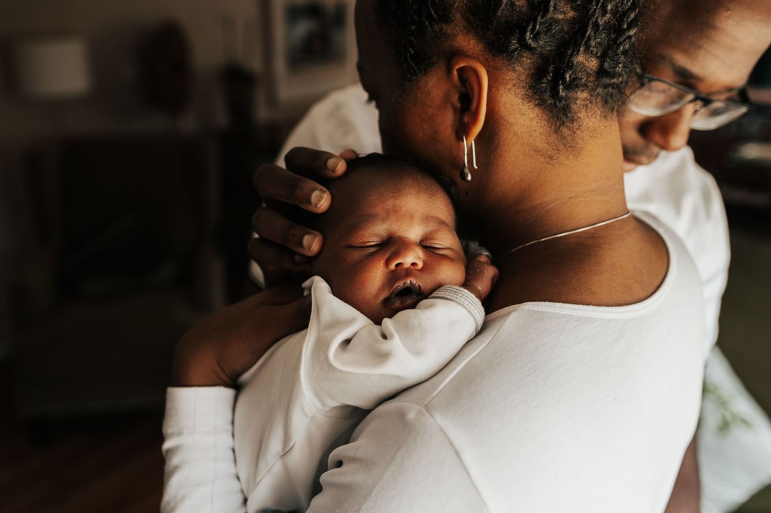 Black Parents Holding Sleeping Newborn Baby On Woman's Shoulder